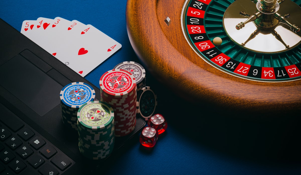 Roda roulette dengan chip, kartu, dan dadu di atas meja kasino
